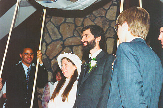 A bride and groom under a chupah, a large covering often used at weddings.